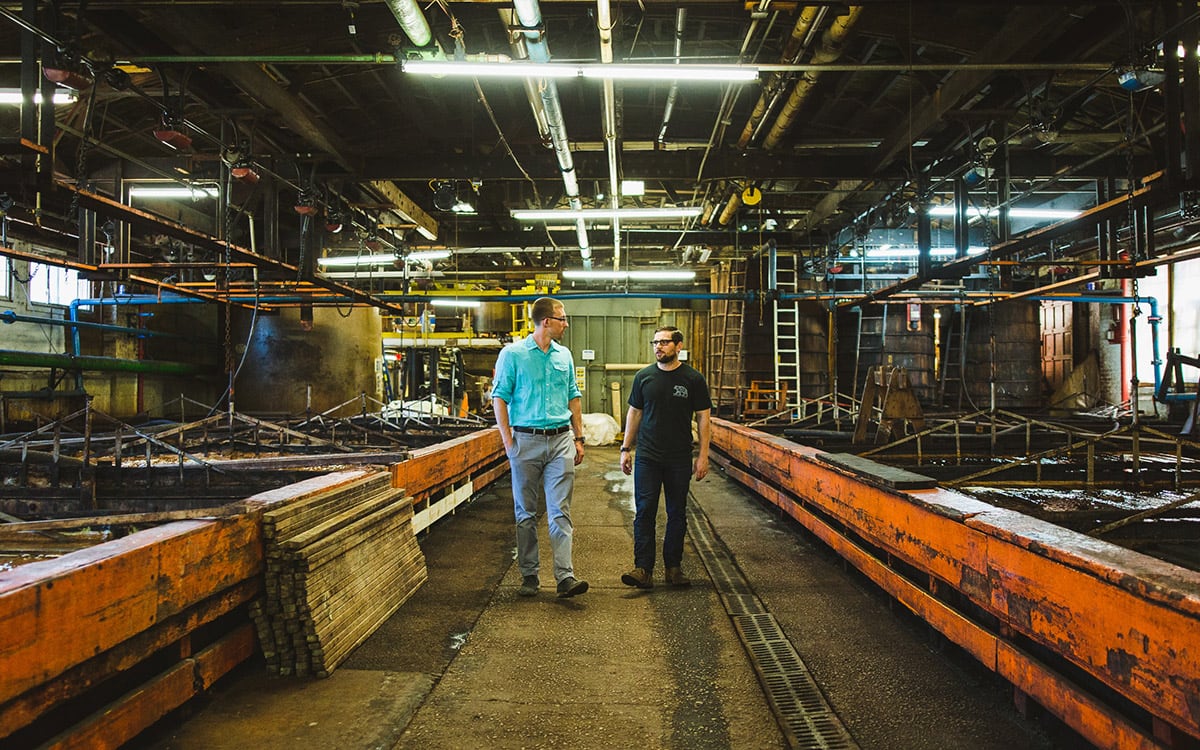 Two men walking side by side through a leather curing facility.