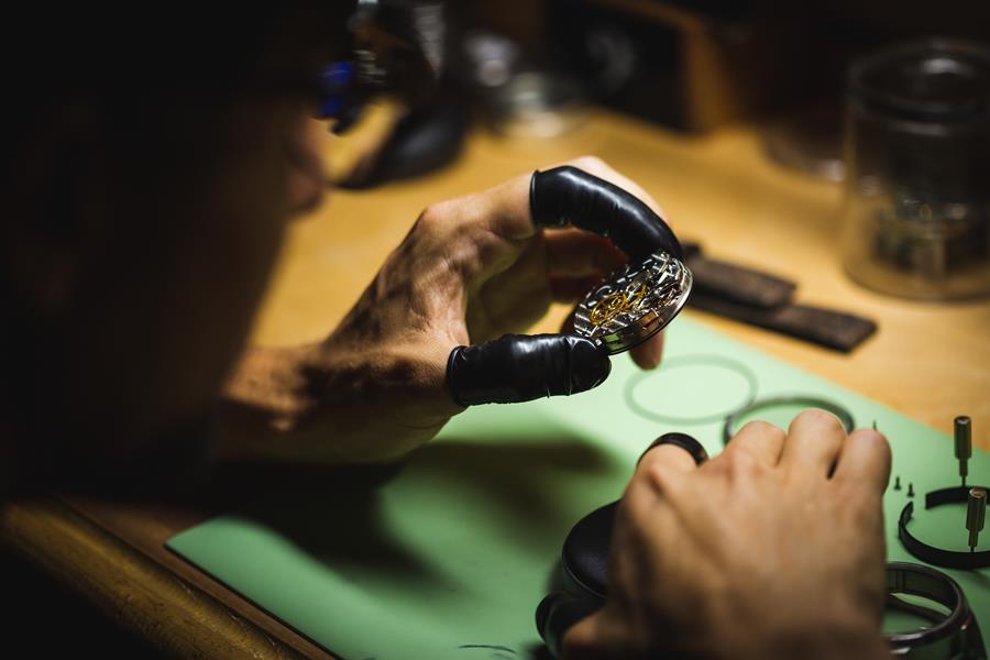 Watch movement held in the hands of a watchmaker. 