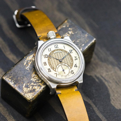 Close up of a watch, titanium case, ornate dial, brown leather strap. 