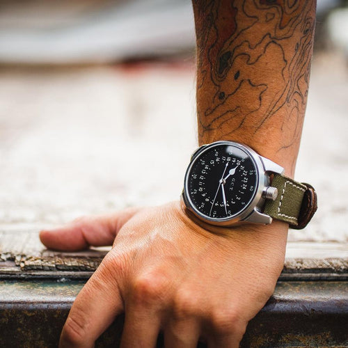 Close up of a watch on a wrist, stainless steel case, black dial. 