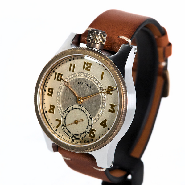 A vintage-style wristwatch with a round silver-toned case, cream-colored dial, black numerals, and a brown leather strap, shown on a plain white background.