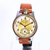 Wristwatch with brown leather strap and gold-detailed face on a white background