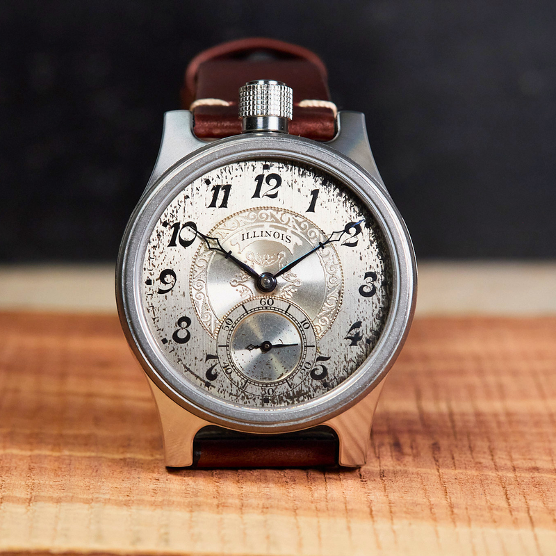 Vintage pocket watch with leather strap on a wooden surface