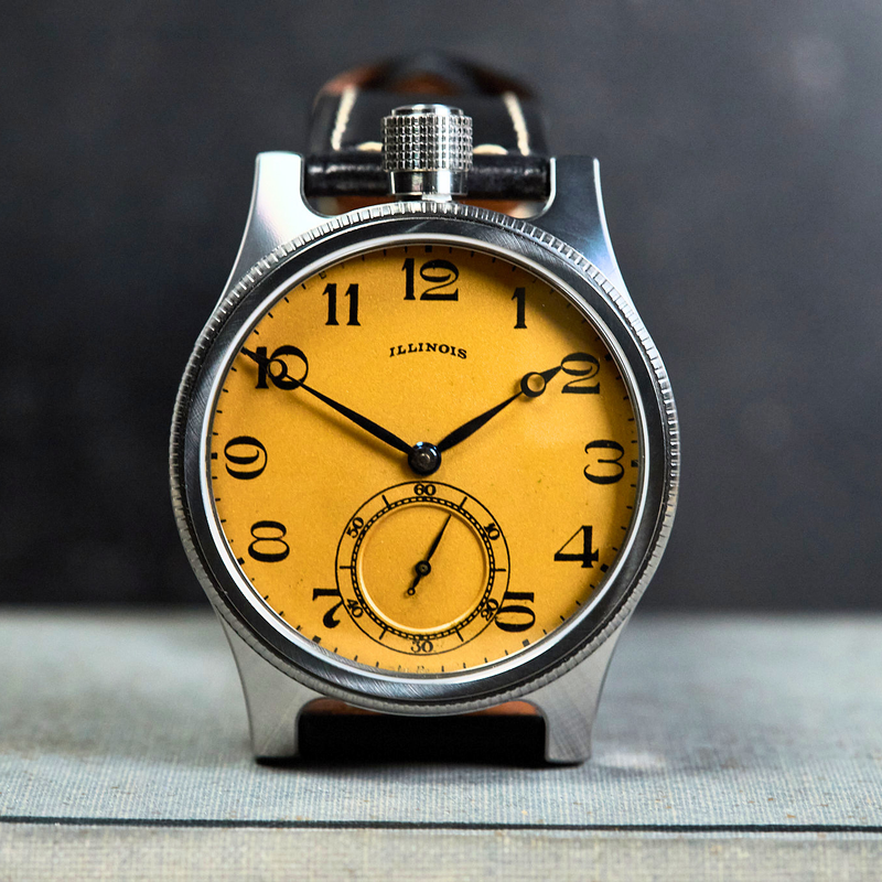 Vintage pocket watch with yellow face and silver casing on a dark background
