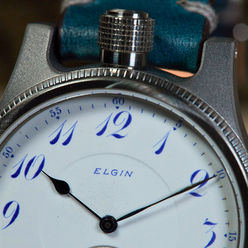 Close-up of a vintage Elgin watch with a blue strap.