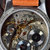 Close-up of a watch mechanism with 'American Artisan Series' branding on a wooden background.
