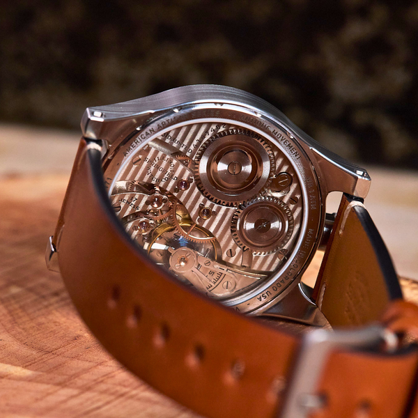 Watch with brown leather strap on a wooden surface