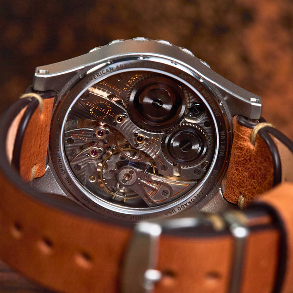 A close-up shot of a skeleton watch with a brown leather strap, showing the intricate mechanical movement through a transparent circular case.