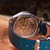 Close-up of a mechanical watch with blue strap on a wooden surface
