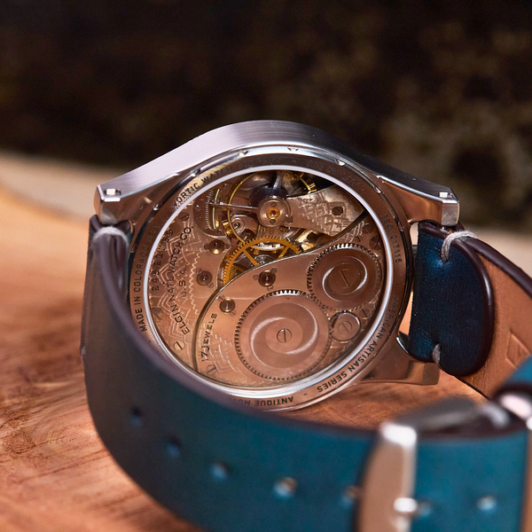 Close-up of a mechanical watch with blue strap on a wooden surface