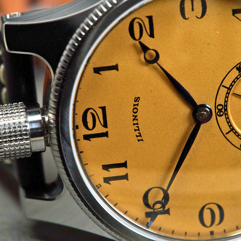 Close-up of a watch with a gold face and 'Illinois' brand name.