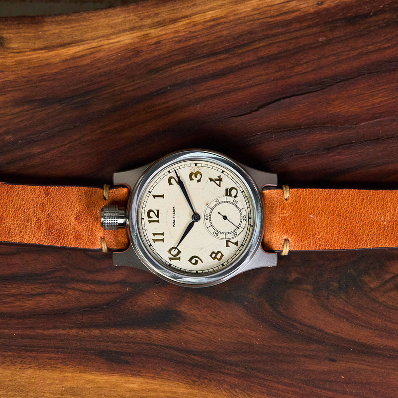 Vintage-style watch with brown leather strap on a wooden surface