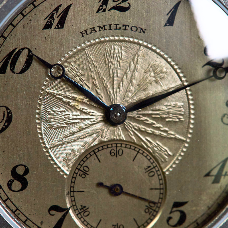 Close-up of a vintage Hamilton watch face with a textured champagne-gold dial, black Arabic numerals, and ornate hands.