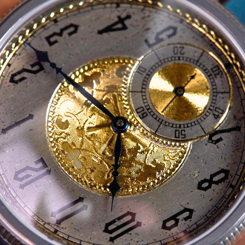 Close-up of a vintage watch with gold mechanical components and silver casing.