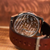 Close-up of a mechanical watch with a brown leather strap on a wooden surface