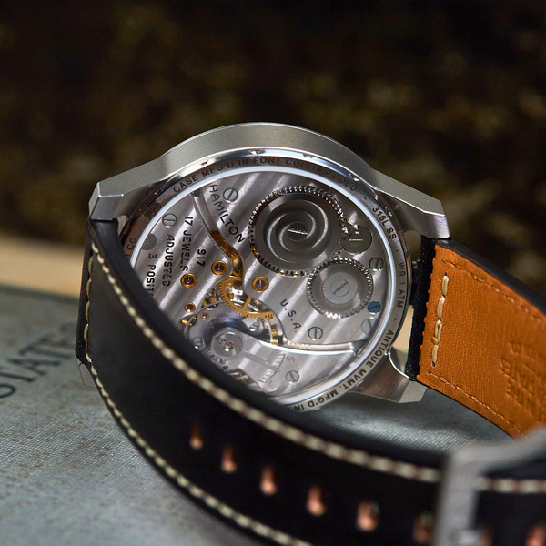 Watch with visible mechanical components on a textured surface