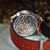 Watch with red strap and visible mechanical components on a textured surface