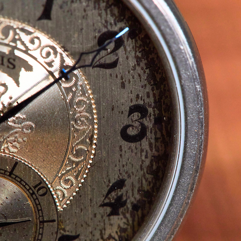 Close-up of an antique clock face with 'Illinois' branding on a blurred background