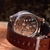 Watch with a brown leather strap on a wooden surface