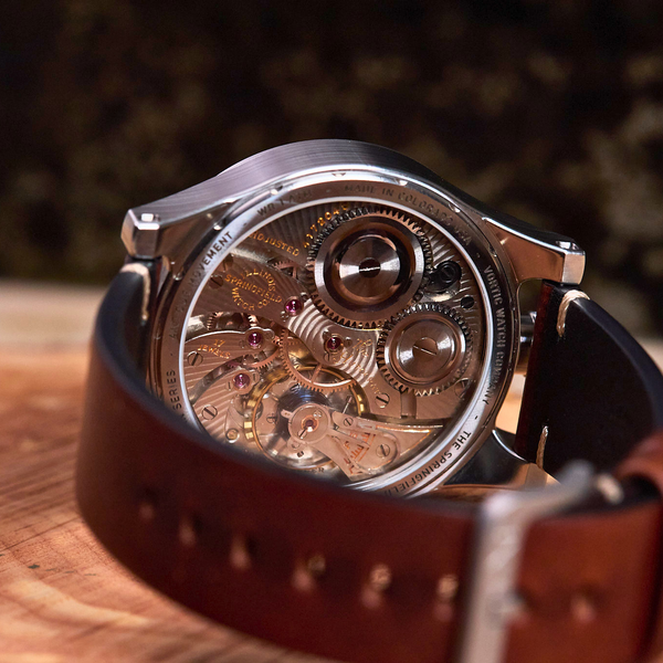 Watch with a brown leather strap on a wooden surface