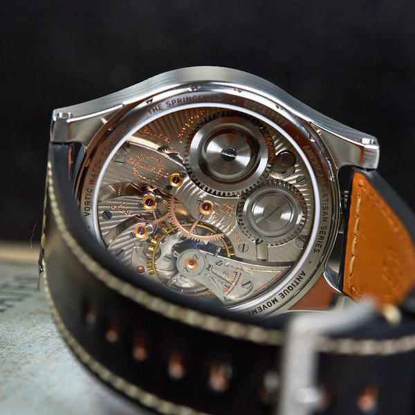 Mechanical watch with open face showing intricate gears on a dark background