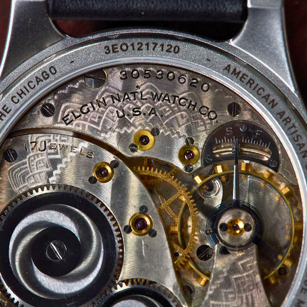 Close-up of a watch mechanism with visible branding on a wooden background