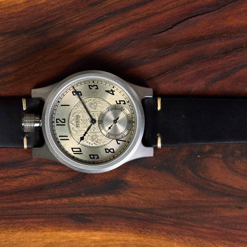 Wristwatch with black strap and silver case on a wooden surface