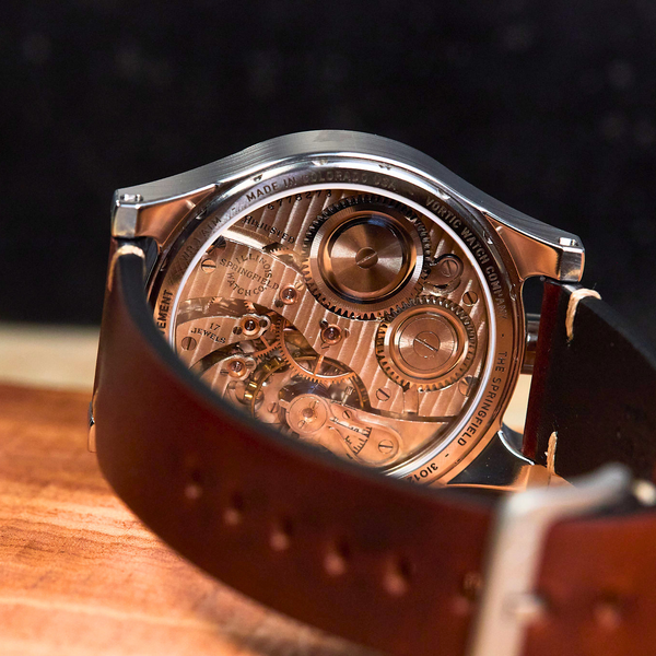 Mechanical watch with brown leather strap on a wooden surface