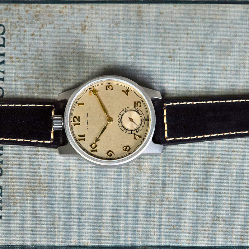 Vintage watch with a black leather strap on an old book