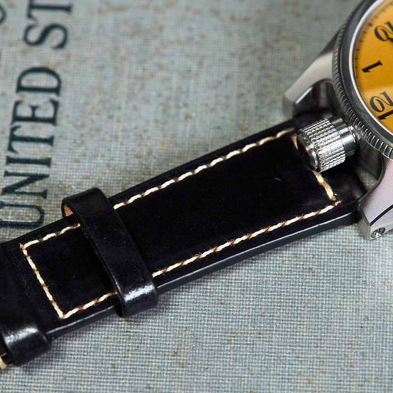 Watch with black leather strap on a textured surface
