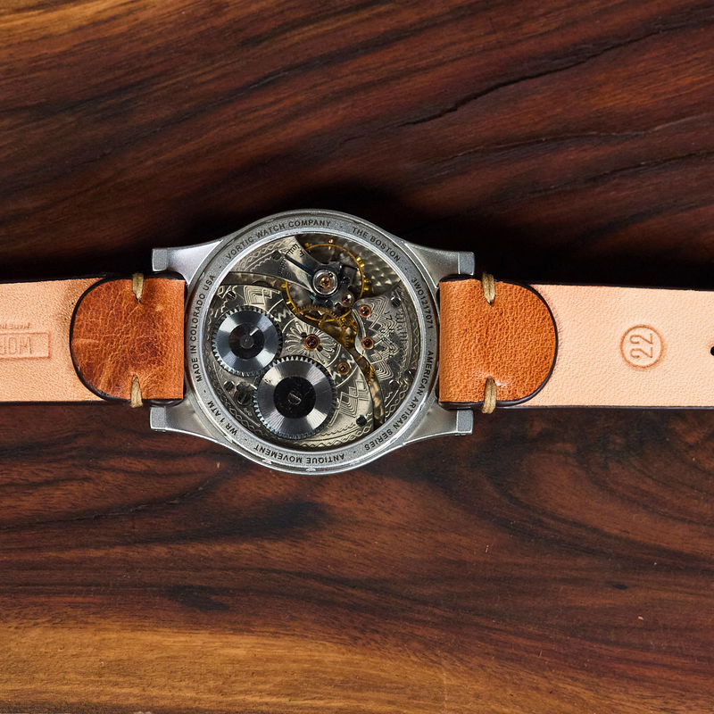 Watch with a leather strap on a wooden surface