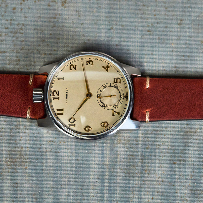 Vintage-style watch with a brown leather strap on a textured surface