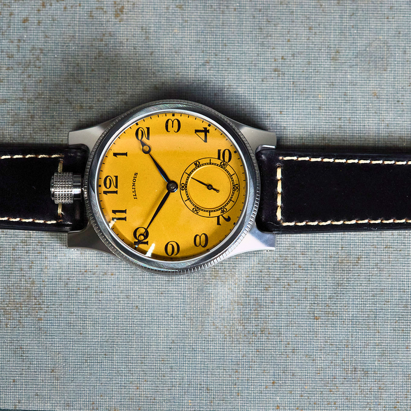 Wristwatch with yellow dial and black leather strap on a textured surface