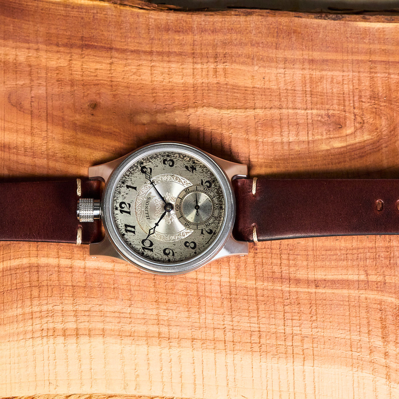 Vintage-style watch with brown leather strap on a wooden surface