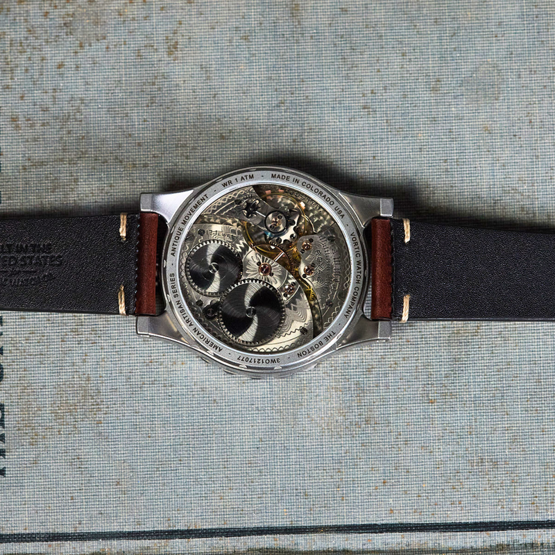 A luxury skeleton watch with a black leather strap and silver-toned case, displayed horizontally on the cover of a vintage book.