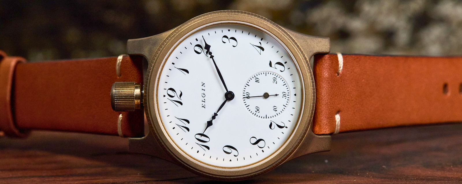 Watch with a brown leather strap on a wooden surface