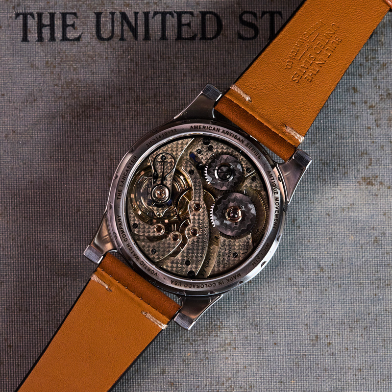Watch with brown leather strap on a book titled 'The United States'