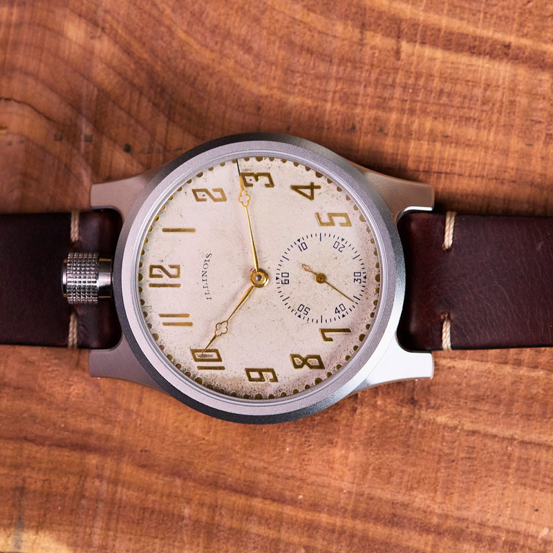 Vintage-style wristwatch with brown leather strap on a wooden surface