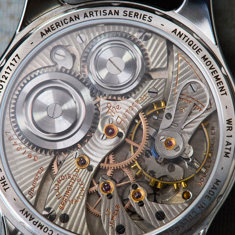 Close-up of a mechanical watch with visible brand names on a textured surface
