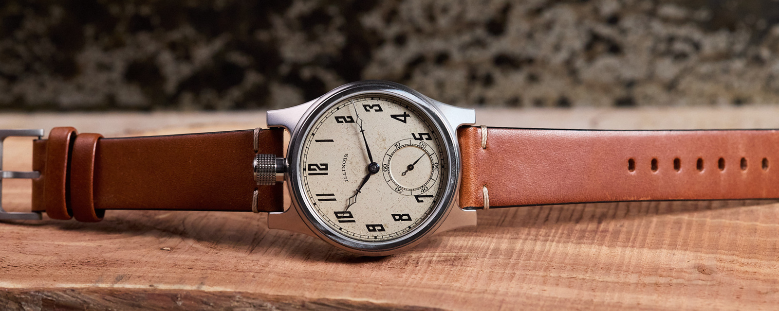 Vintage-style watch with brown leather strap on a wooden surface