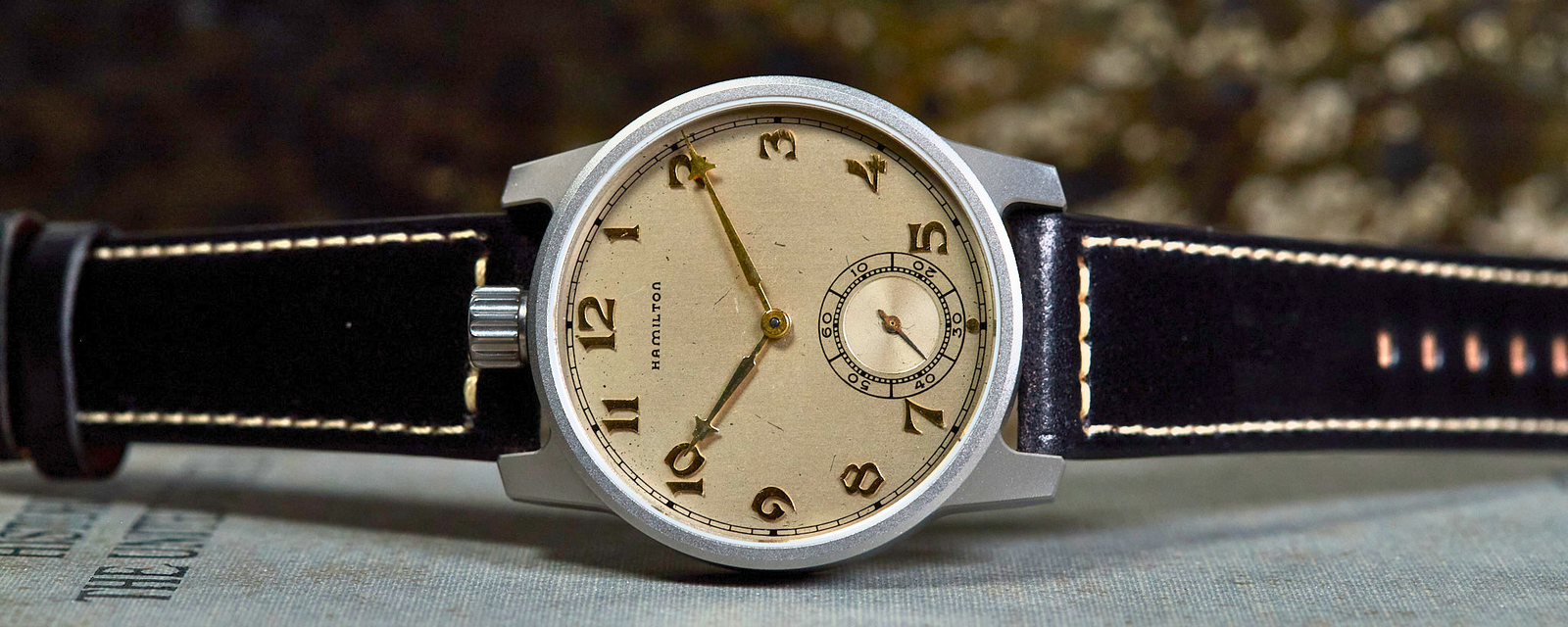 Vintage wristwatch with a black strap on a textured surface