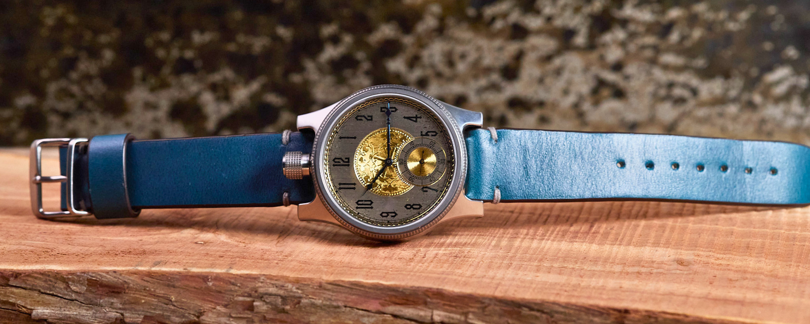 Wristwatch with blue leather strap on a wooden surface