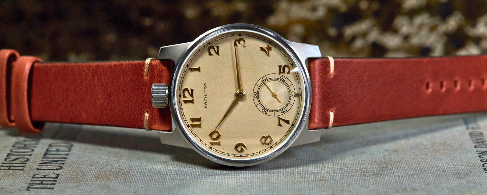 Wristwatch with a red leather strap on an old book