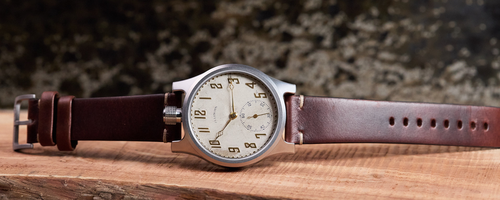 Vintage-style wristwatch with brown leather strap on a wooden surface