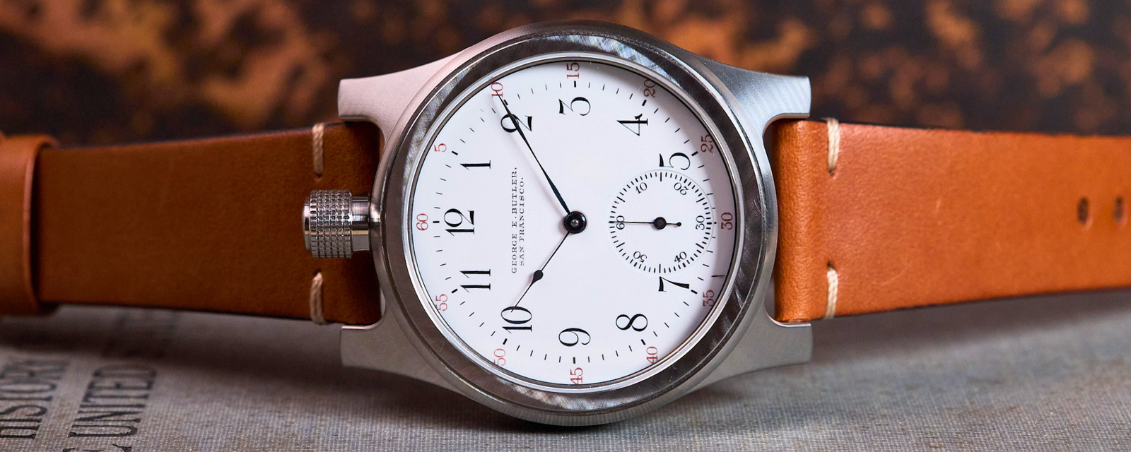 Watch with a brown leather strap on a textured surface